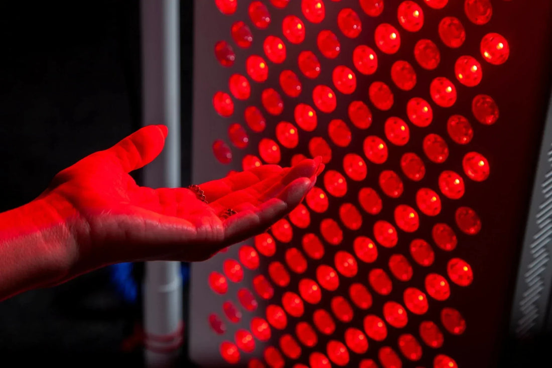 A close-up of a person using a red light therapy device on their knee for inflammation relief, with a soothing red glow.